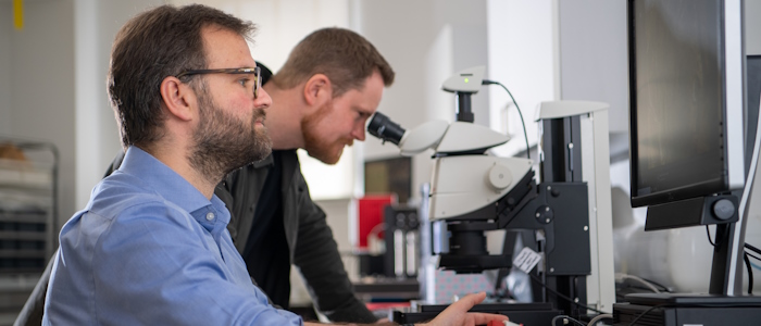Two researchers study a roman coin in a lab